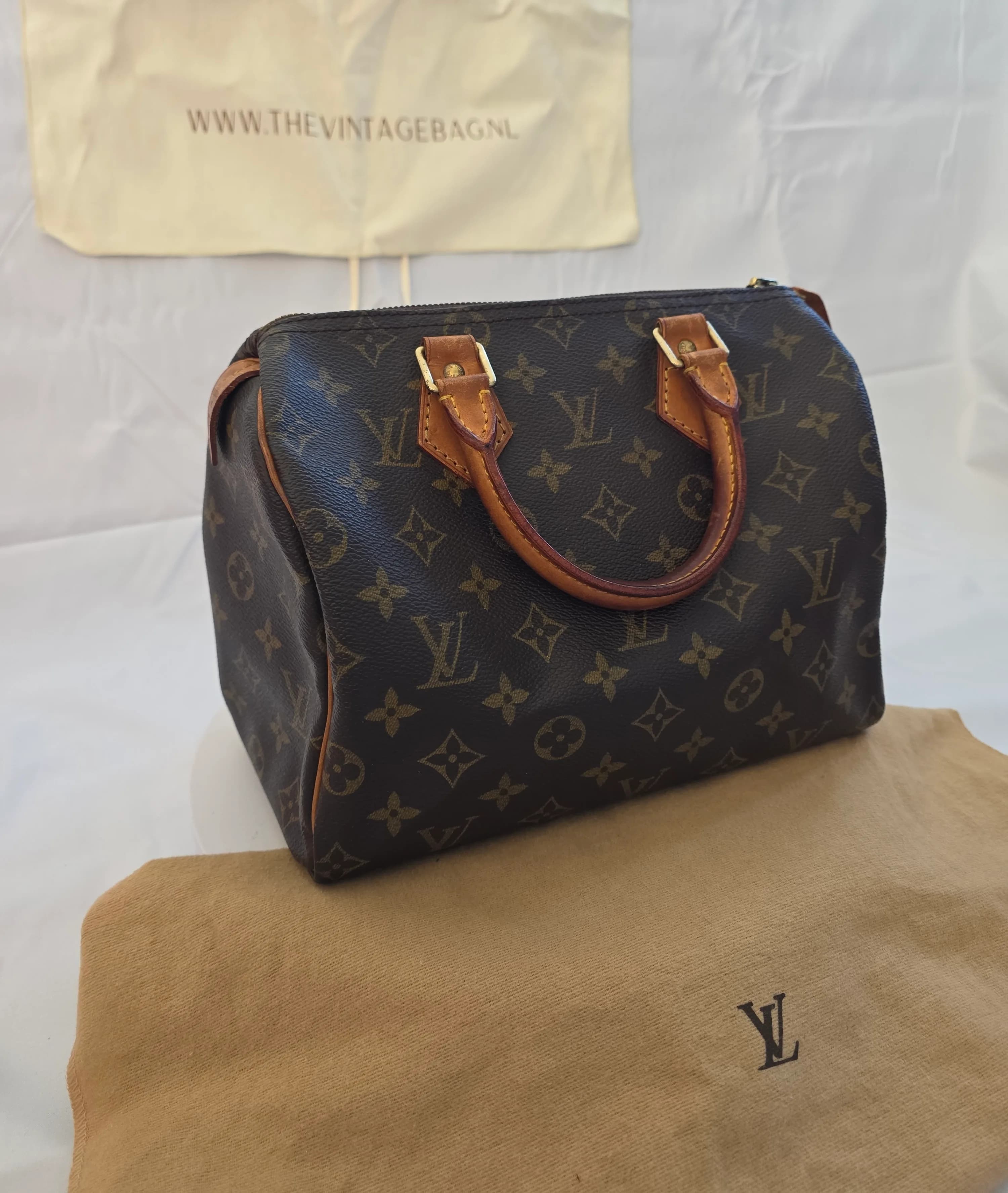 Vintage Louis Vuitton Speedy 25 in Monogram canvas met leren handvatten, schuin van voren, staand op de originele dustbag